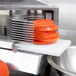 A Nemco tomato slicer with sliced tomatoes on a counter.