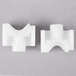 Two white plastic pieces on a gray surface.