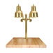 A brass Hanson Heat Lamp on a wooden surface with a maple block and gravy lane.
