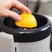 A hand squeezing an orange into a juicer.