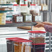 A woman's hand slides a gray label holder into a shelf holding food containers.