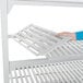 A person's hand holding a white Cambro Camshelving premium vented shelf.