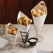 A table with food served in American Metalcraft cardboard fry cones.