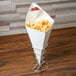 A white paper square cone filled with french fries on a table.