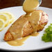 A plate of chicken with yellow mustard sauce and a lemon slice.