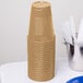 A stack of Creative Converting Glittering Gold plastic cups.