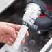 A person holding a Bar Maid shot glass washer brush.