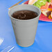 A shimmering silver plastic cup filled with liquid on a blue table.