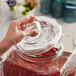 A person using an Acopa glass lid to cover a beverage dispenser on a table.