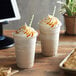 Two cups of Big Train caramel latte blended ice coffee with whipped cream and caramel sauce on top.