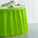 A table with a Fresh Lime Green plastic table skirt on a table with green tablecloth and cupcakes.