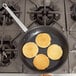 A Vollrath non-stick fry pan with small pancakes cooking on a stove.