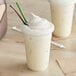 Two cups of white Big Train Fit Frappe Vanilla Protein Drink with whipped cream and straws.