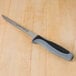 A Dexter-Russell V-Lo fillet knife with a black handle on a wooden table.
