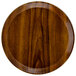 A Cambro round fiberglass tray with a Burma teak finish.