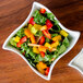 A white American Metalcraft wave porcelain bowl filled with a vegetable salad.