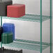 A Regency green wire shelf with plastic containers holding blue and green bowls and green plates.