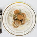 A Fineline Silver Splendor plastic plate with meatballs, cheese, and a knife and fork.