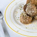 A Fineline Silver Splendor plastic plate with meatballs and cheese with a fork.