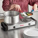 A chef using a Galaxy double burner countertop range to cook food in a pan.