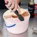 A hand using a Zeroll ice cream scoop to scoop ice cream.