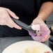 A person using a Zeroll Zerolon ice cream scoop to scoop ice cream.
