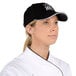 A chef wearing a black Chef Revival baseball cap with a white logo.