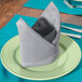 A folded Intedge gray polycotton napkin on a plate.