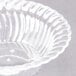 A clear plastic Fineline Flairware bowl with a scalloped edge.