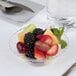 A Fineline clear plastic bowl filled with fruit on a table.