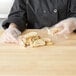 A person in a chef's uniform holding a plastic bag of bread.