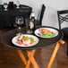 A Tavern Tan non-skid oval serving tray with food and wine on a table.
