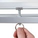 A hand turning a metal bar to adjust a Luxor whiteboard stand.