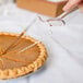 A person using a Fineline clear plastic pie server to cut a pie.