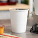 A white Choice paper hot cup filled with a drink on a table.