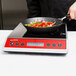 A person using a Vollrath Carbon Steel Non-Stick Fry Pan to cook vegetables on a stove.