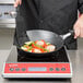 A person cooking food in a Vollrath Carbon Steel Non-Stick Fry Pan on a stove.