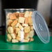 A Carlisle clear plastic crock with a lid filled with croutons.