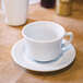 A Tuxton bright white china cup on a saucer.