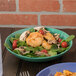 A bowl of salad with shrimp and tomatoes in a GET Diamond Mardi Gras melamine bowl.