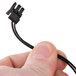 A hand holding a black cable with a small connector.