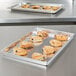 A Vollrath aluminum party pan filled with pastries on a counter.