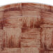 A brown Cambro round fiberglass tray with a basketweave pattern on a wood surface.