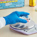 A gloved hand holding a container of pills.