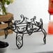 A black metal stand for an Acopa glass beverage dispenser on a table.