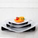 A stack of white Elite Global Solutions square plates with rounded edges on a white background.