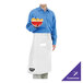 A man in a white Chef Revival bistro apron holding a bowl of fruit on a counter in a professional kitchen.