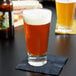 An Anchor Hocking cooler glass filled with beer on a table.