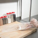 A person in gloves using an ARY VacMaster vacuum packaging bag to hold chicken.