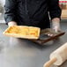 A chef holding a Gobel fluted rectangle quiche pan with a pie in it.